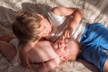 Kız ve erkek kardeşim birlikte oynama. Dört yıl yaşlı erkek çocuk kız kardeşi ile oynuyor. Yeni doğan bebek kanepede ağabeyi ile yalan. Çocuklar yatakta. Kardeşim onun küçük kız kardeşi arıyor. Kardeş Shan