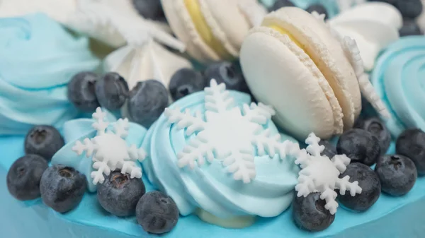 Delicious cake for the holiday of berries, color blue with blueberry. Sweet cookery. Winter cupcakes, biscuits. Healthy sweets concept. Close-up. Snowflakes on blue light cake.