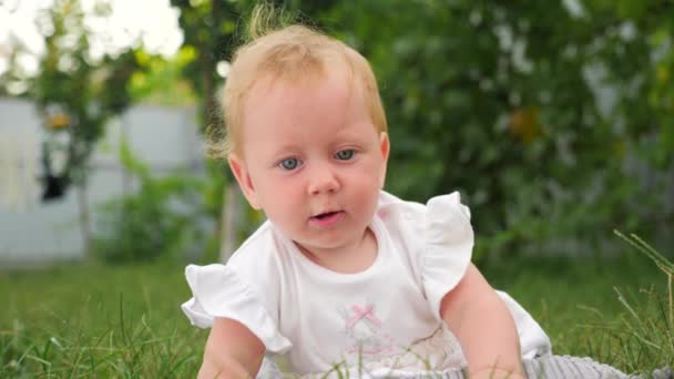 Baby och natur. Baby tandsprickning bakgrund. Baby barnsjukdomar. Barnet ligger på grönt gräs. Barn leker i trädgården. Tänder skär genom. — Stockvideo