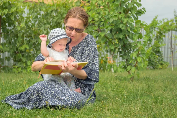 有孩子的女人有孩子的工作妇女 读这本书和玩婴儿 外婆和孙女在一起快乐的育儿背景 生成连接 复制空间 — 图库照片
