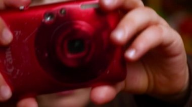 Çocuk alarak fotoğraf ile fotoğraf makinesi. Kırmızı kamera elinde genç bir film yapımcısı. Çocuk 4-5 yıl yaşlı sıkılıyorum. Rol oyunları. Kamera holding eller. Animasyon Okulu. Genç film yapımcısı. Film yapımı arka plan. Kamera flaşı. Genç yönetmen elinde kamera.