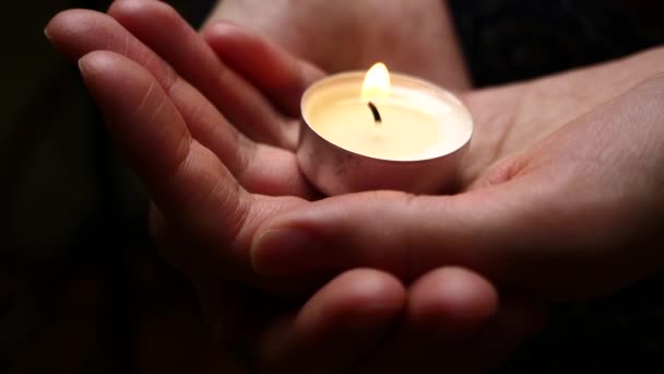 手をキャンドルします クローズ アップ 女性の手に蝋燭の照明の背景 慈悲の背景 悲しみのコンセプトです 記念の背景 — ストック動画