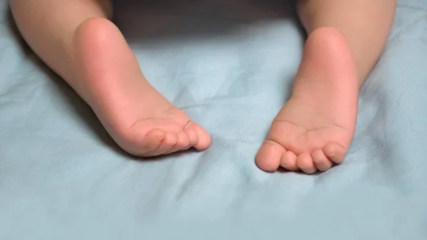Early start. Infant's development in 7 - 12 months. Baby's closeup little barefeet. Children's feet. Barefeet on the bed. Kid's feet in bed. Heels and toes on bed. Heels and feet. Copy space.