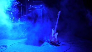 Rock konseri arka planı. Sahnede elektro gitar kaldı. Konserde duman. Gece kulübünde müzik ışıkları, konser, festival. Konser konsepti. Rock konserinin arka planı. Stüdyo reklamı.