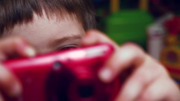 Caméra rouge dans les mains du jeune cinéaste. Yeux de l'élève préscolaire. Equipement média. Arrière-plan d'anamtion. Jeune photographe d'origine. Concept d'éducation préscolaire. Créativité et éducation . — Video