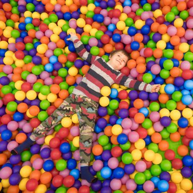 Küçük bir çocuk havuza kreş plastik topları ile oynarken. Çocuk yüzme vardır. Yakın çekim, gerçek zamanlı, yapay ışık, kapalı. Ruh sağlığı kavramı. Montessori kavramı. Mutluluk kavramı.