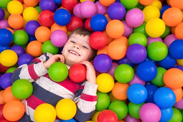 Menino brincando na piscina com bolas de plástico no berçário. Atividades internas para crianças. Desenvolvimento de fundo emoções positivas. Fundo de férias . — Fotografia de Stock