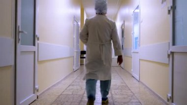 Yetişkin erkek doktor hastane salonunun önünden geçiyor. Hastanenin manzarası. Doktorla boş klinik koridoru. Özel klinik, tıp merkezi. Geleneksel olmayan tıpta tıbbi reform.