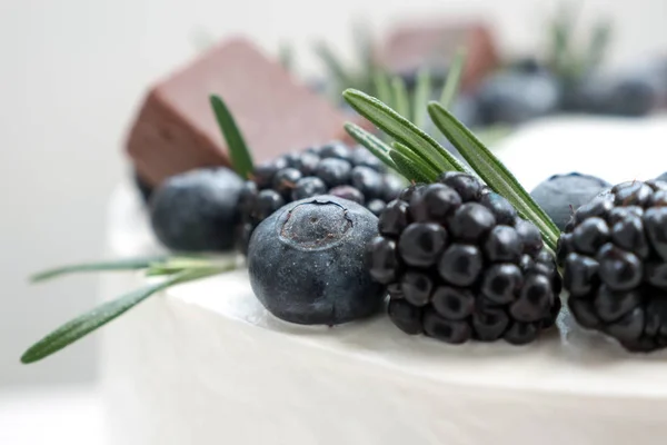 Cake decorating with blueberry and blackberry with rosemary. Cake shop concept. Wedding cake close-up. Birthday cake.