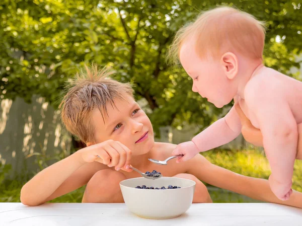 Οι σιβινγκς τρώνε φρέσκα ζουμερά μούρα. Καλή ιδέα για την παιδική ηλικία. Υγιεινά φαγητά. Υγειονομική περίθαλψη των παιδιών. Ένα νήπιο που τρώει μούρα με το κουτάλι. Βιολογικό φαγητό. Καλοκαιρινά μούρα από τον κήπο. — Φωτογραφία Αρχείου