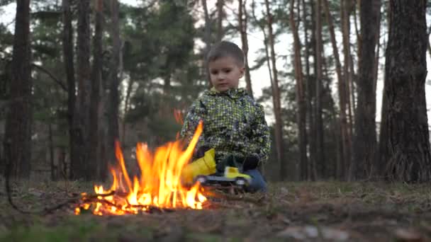 Drengen stirrer på pejsen. Brandstiftelsesbaggrund. Smukke dreng, der varmer op ved ilden. Når krig kommer til det indfødte hjem. Flygtningebaggrund. Udforskning af verden . – Stock-video