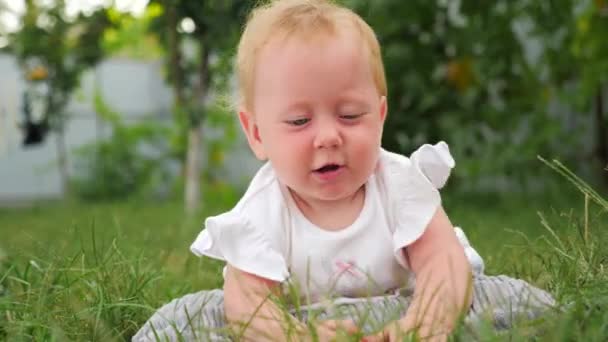 新鮮な空気の女の赤ちゃん。モンテッソーリのコンセプト。脳の発達赤ちゃんの発達の背景。子供と自然前の緑の草の上で日光浴をする赤ちゃん、裏庭. — ストック動画