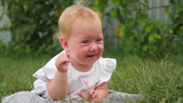 Spädbarn på amning. Happy Childhood koncept. Happy mors dag. Blåögda flicka leende utomhus. Liten vacker flicka som ligger på gräset i början av höstdagar. Flickan utforskar världen runt henne — Stockvideo