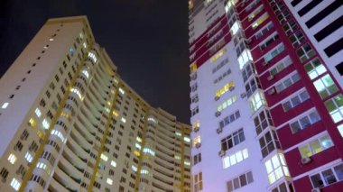 Geceleri aydınlatmalı bina pencerelerinin gece saatlerinde balkonlu dairelerde yaşayan insanlarla birlikte. Elektrik tüketim konsepti. Aşağıdan görüntüleyin. Akşam ları şehir caddesi. Konutların pencerelerinde ışık. Zaman atlamalı. İş merkezi açık