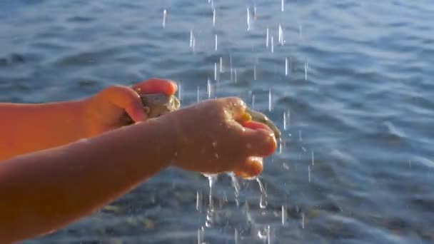 欧洲炎热的夏日。孩子们手在水滴下,背景是大海。纯水背景。水滴与手在海水背景。异常炎热的夏季 — 图库视频影像