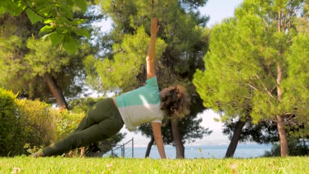 Europeisk kvinna som gör yoga och avslappningsövningar utomhus. Sunt kropps koncept. Morgon övningar på frisk luft. Kaukasiska damen gör yoga på framsidan varvet — Stockvideo