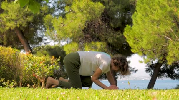Mulher fazendo pose de ioga. Exercícios matinais no jardim, quintal. Férias de verão perto do mar. Moradia perto do mar. Fortalecimento do fundo do corpo . — Vídeo de Stock