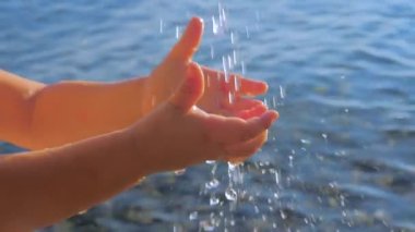 Bebek elleri. Küçük bebek deniz manzarası arka planda temiz suda el yıkama. İçecek su ve deniz suyu kavramı. Küçük parmaklar dalgalı deniz arka plan üzerinde su damlaları dokunun. Pediatri, çocuk doktoru