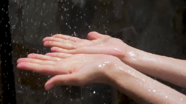 Wassertropfen tropfen auf Frauenhände. Zauberhaftes Spektakel. Wasser als Quelle des Lebens. Wassertropfen auf Frauenhände, — Stockvideo