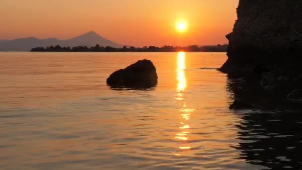 Tramonto sul mare con montagna sullo sfondo. Sera vicino al mare, oceano. Paesaggio marino meditativo con più sole sul backround. Mare di vongole. Acqua liscia di oceano colorato in luci del tramonto. Il sole tramonta — Video Stock