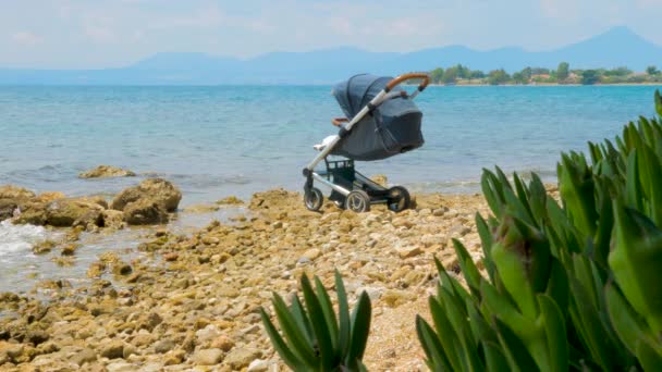 Baby fordon nära havsvatten i Grekland. Hälsosam luft nära havet för barn. Småbarn transport med Seascape på bakgrunden. Barnvagn på stranden. Baby sova i sittvagn vid havet — Stockvideo