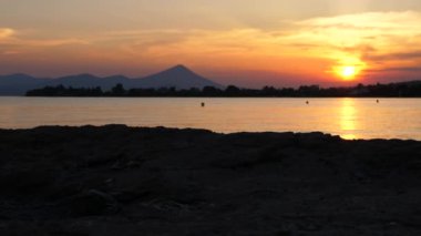 Seyahat konsepti. Turizm geçmişi. Duygular ve romantik arka plan. Sakin doğa dokusu. Deniz kıyısında gün batımı. Arka planda dağlar ve gün batımı ile Seascape.