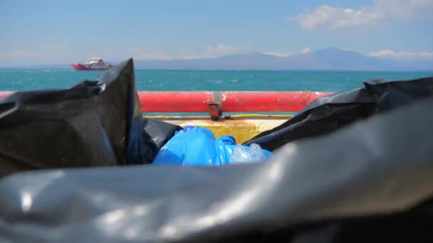 Basura de plástico envasada en bolsa en barco en el mar. Plástico del mar sobre fondo marino. Barco en el horizonte mientras basura en paquete de celofán en el barco, barco. Plástico extraído del mar . — Vídeo de stock