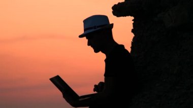 Pitch'e hazırlanıyorum. Gün batımında sahilde bir dizüstü uzaktan çalışma ile erkek serbest hipster. Çalışan geçmişi. İnternet üzerinden online çalışma. Ağ kalitesi. Mutlu tatiller zaman kavramı.