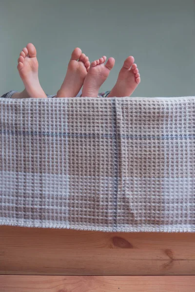 Босоногие дети на деревянной кровати, покрытой одеялом . — стоковое фото