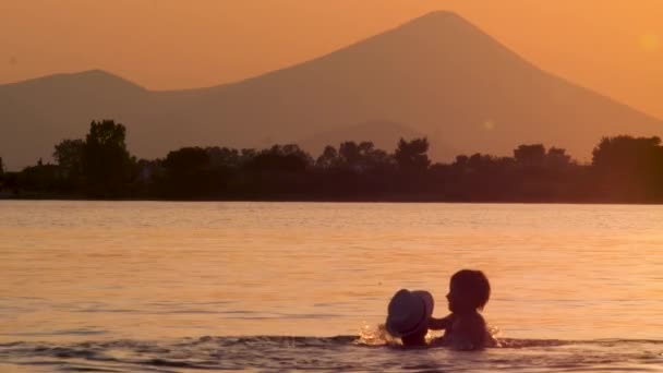 Père et fils s'amusent dans l'eau, mer au crépuscule sur fond. Père heureux passe du temps avec l'enfant dans la mer sur fond de montagne flèche. Santé mentale et physique. Concept d'amitié — Video