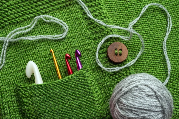 El işi geçmişi. Çelik ve plastik kancalar örgü süveterin cebinde. El yapımı arka plan. El işi konsepti. Tığ işi ve örgü fikri. El yapımı ekipmanlar. Boşluğu kopyala