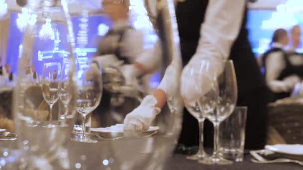 Een ober dekt de tafel in een restaurant voordat de klanten arriveren, en maakt gebruik van fijn bestek en glazen. Concept van: catering, design, romantische diners. Luxe catering achtergrond. Feestidee — Stockvideo
