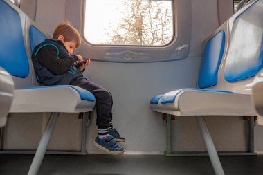 4G, 5G internet bağlantısı konsepti. Cep telefonu olan çocuk nakliyede. Seyahat konsepti. Elektronik harita konsepti. Pencerenin yanında oturan genç gezgin telefona bakıyor.