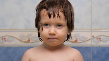 Duş aldıktan sonra güzel yeşil gözlü küçük kızın yüzü. Islak suratlı ve saçı banyoda duran çocuk. Banyo yaptıktan sonra şirin bir çocuğun portresi. Deri bakımı konsepti. Pediatri arka planı
