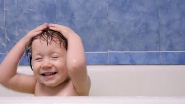 Banyoda banyo yapan pozitif küçük bir kız. Tatlı Avrupalı kız banyoda mutlu bir şekilde banyo yapar. Çocuk banyo yapıyor. Banyoda suyla oynayan mutlu küçük kız. Banyodaki oyuncu çocuk.