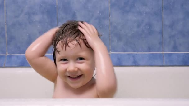 Het kind spettert water in de badkamer. Klein gelukkig meisje baadt in de badkamer. Vrolijk kind speelt met water. Een kind dat in bad gaat. Meisje dat met water speelt. Kind heeft plezier. Heerlijk kind hebben plezier — Stockvideo