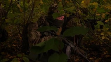 Ormanda maskeli komandolar. Tüfekli bir asker yakından izliyor. Özel kuvvetler pusuda saklanıyor, saldırıya hazır..