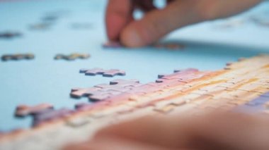 Yapboz monte ediliyor. Kilitleme sırasında evde kalmanız gerektiğinde eğlence için yapbozun parçaları. Bütünün bir parçası. Aile aktivitesi. Bir bölüm öğrenmek için görevlendirildim. Boş zaman arkaplanı