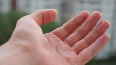 Avuç içi yağmur damlaları. Ev konseptine bağlı kalmak. Yağmurlu bir gün, su damlalarını elle yakalamak. Mutlu bir yaşam tarzı. Elin yağmur damlalarıyla oynuyor. Ekoloji konsepti. Mutlu yağmurlu günler. Kuraklık günleri bitti.