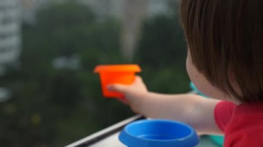 Yağmur damlası yakalayan çocuk. Ev konseptine bağlı kalmak. Yağmurlu bir gün, su damlalarını tabakla yakalamak. Mutlu bir çocukluk. Montessori konsepti. Ekoloji konsepti. Mutlu yağmurlu günler. Dokunsal duygular gelişiyor.