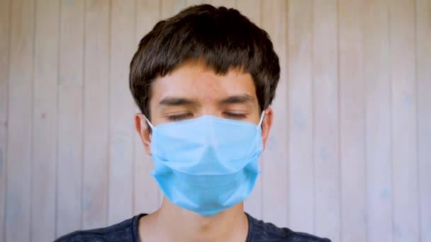 Een jongen in een medisch gezichtsmasker die naar de camera kijkt. Coronavirus, covid-19 uitbraak. Bruine ogen van een 6-jarige jongen met masker. Virus, bacteriën, epidemie uitbraak. Gezondheidsregels ter bescherming tegen coronavirus — Stockvideo