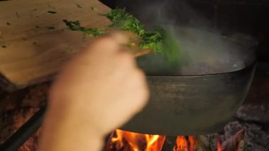 Açık hava şömine ocağı. Tuğla ve taşlardan yapılmış ateş yakıyor. Fırında açık ateşte yemek pişirmek. Yiyecek dolu demir kazanlar.