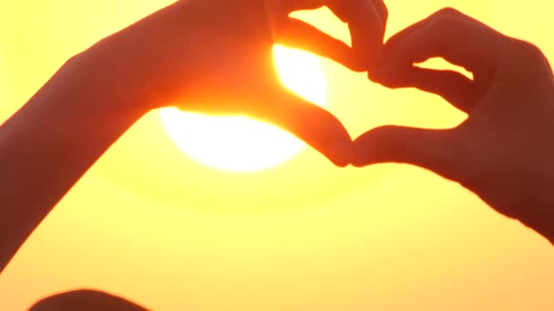 Coeur en forme avec les mains sur le coucher du soleil lever du soleil par l'océan ou la mer. Vidéo de haute qualité du symbole de l'amour et de la liberté au lever du soleil. Un concept adorable. Signe de coeur avec espace de copie — Video