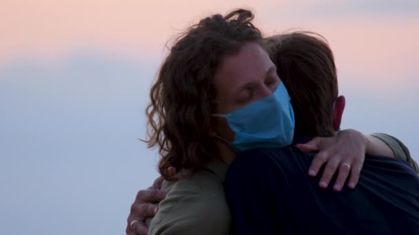 Exciting couple in love with face masks waiting for a test for coronavirus. Couple in protective masks embracing each other against a beautiful, clear sky during quarantine, the Covid-19 epidemic — Stock Video
