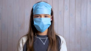 Alnında koruyucu tıbbi maske takan koyu renk saçlı güzel bir kızın portresi. Koruma konsepti. Bayan bayan virüs koronasını engelliyor. Sosyal uzaklık, karantina. Tek kullanımlık maskelerin komik kullanımı.