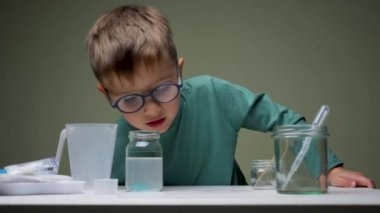 Gözlüklü çocuk evde pipet ve sıvı ile kimyasal deneyler yapıyor. Öğrenme, faiziyle öğrenme. Alternatif eğitim. Araştırma geçmişi. Başarılı öğrenim için kişisel nitelikler