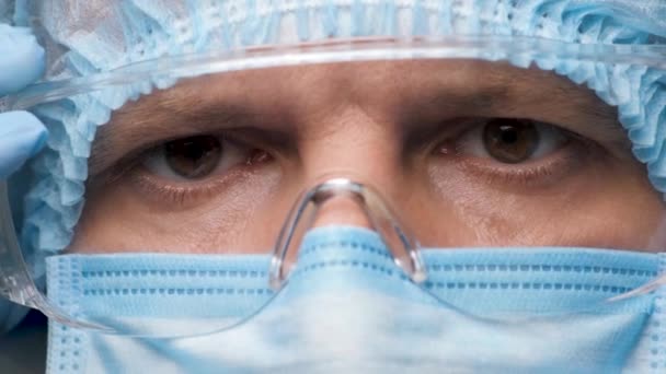Güvenilir Doktor 'un ya da Kişisel Koruyucu Malzeme' deki Sağlık İşçisi 'nin gözleri ameliyata hazırlanıyor. Covid-19 sırasında güvenlik üniforması ve koruyucu gözlük takan bir doktor. Araştırma Laboratuvarı Görevlisi — Stok video