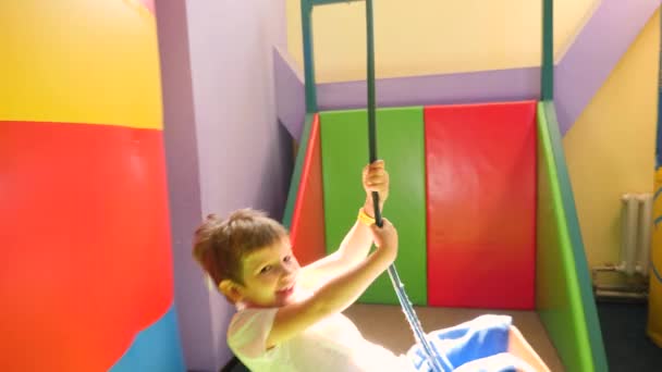 Glücklich lächelnder Junge auf der Seilrutsche im Indoor-Unterhaltungszentrum für Kinder. Fröhliches Kind, das Spaß an der Seilrutsche hat, lächelt im Vergnügungszentrum für Kinder. Indoor-Spielplatz auf dem Seil. — Stockvideo