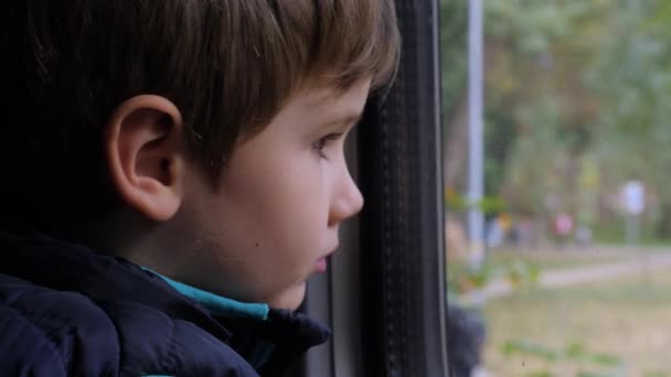 Utazó gyerek, kinézett az ablakon. Hild vonattal. A fiú a szülővárosából a nagyvárosba megy. Nosztalgia a gyermekkori fogantatásért. Játszótér az ablak előtt.Boy Journey to the New. Közelkép