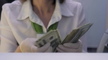 Muhasebeci Koruyucu Eldiven 'de dolar sayıyor. Banka çalışanı 100 Dolarlık banknotları tekrar sayıyor. Veznedar döviz bürosunda Amerikan Banknotlarını yeniden sayıyor. Banka Nakit Departmanı. Mali işler